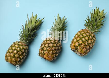Three tasty ripe pineapples on blue background Stock Photo