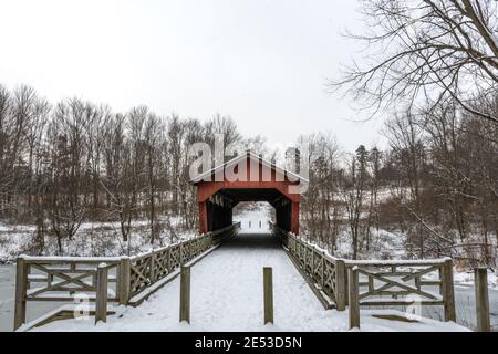 St. Clairsville, Ohio/USA- January 15, 2019: Snow-covered, historic Shaeffer Campbell Covered Bridge and the frozen College Pond with surrounding fore Stock Photo