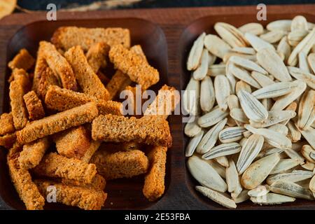 Crackers and sunflower snacks on wooden plate Stock Photo