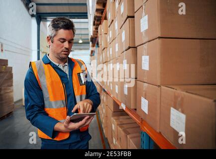Factory technician working using digital tablet at factory warehouse Stock Photo