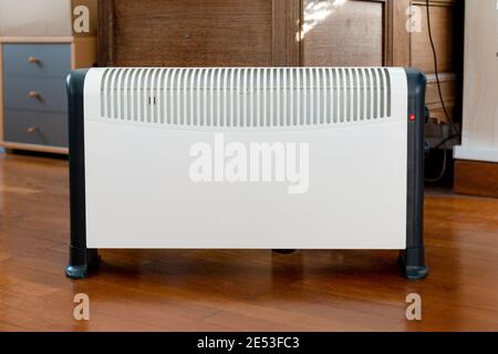 Electric heater on parquet floor at home Stock Photo