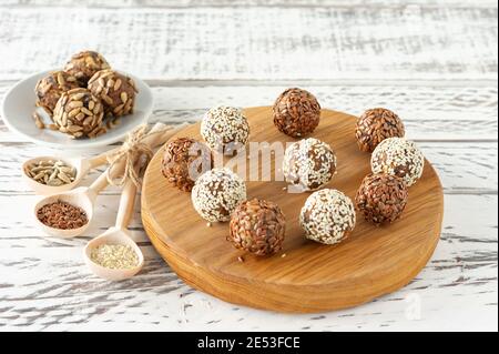 Healthy raw energy balls. Candy vegan balls of dates, coconut pulp, nuts on a wooden desk. Concept of useful homemade no sugar candies. Stock Photo