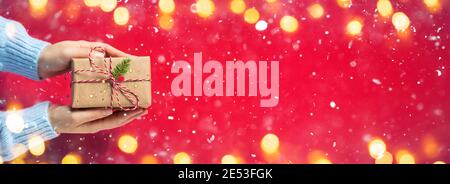 Woman Hands Giving Rustic Present With Snowing And Lights Stock Photo