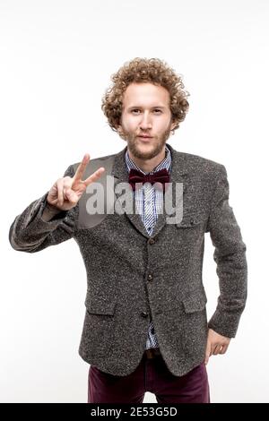 Young curly-haired businessman wearing brown suit gesturing with a V-sign on a white background. World. isolate. Stock Photo
