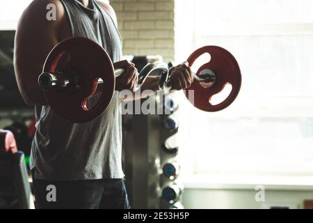 Silhouette photo of a muscular young athlete doing exercises with a barbell in the gym. Power training Stock Photo