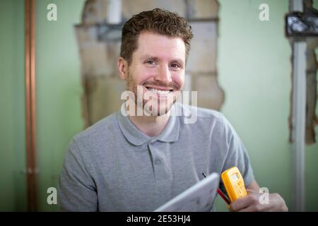 Portrait Of Electrician Inside House Being Renovated Studying Plans Stock Photo