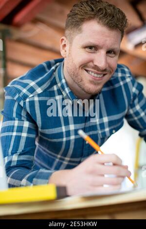 Portrait Of Architect Inside House Being Renovated Working On Plans Using Laptop Stock Photo