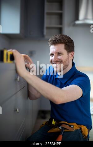 Portrait Of Carpenter Installing Luxury Modern Fitted Kitchen Stock Photo
