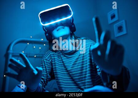 Teenage Girl At Home In Bedroom Wearing Virtual Reality Headset At Night Stock Photo
