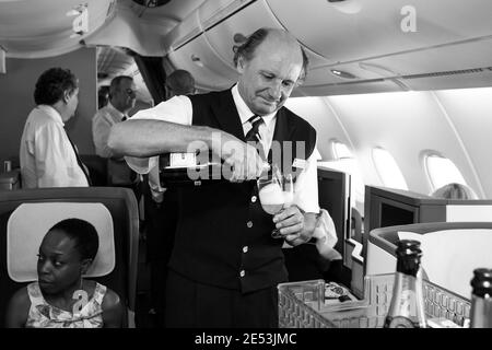 JOHANNESBURG, SOUTH AFRICA - Jan 06, 2021: Johannesburg, South Africa - February 06, 2014: Male cabin crew pouring a glass of Champaign in business cl Stock Photo