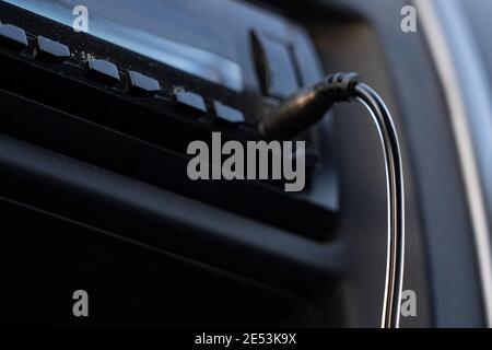 Aux cable inserting on car audio to play music from mobile phone Stock Photo