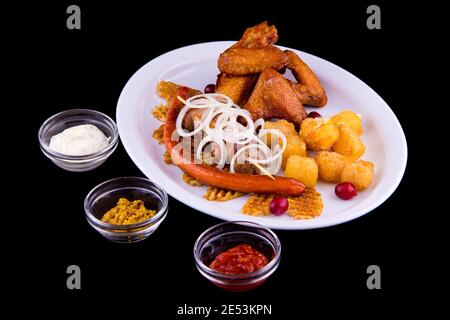 Large beer set of fried snacks - chicken wings, pork skewer, homemade sausages, potato chips, deep-fried cheese, onion, three sauces: white, red, must Stock Photo
