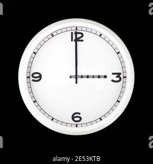 White round analog wall clock isolated on black background, its three oclock. Stock Photo