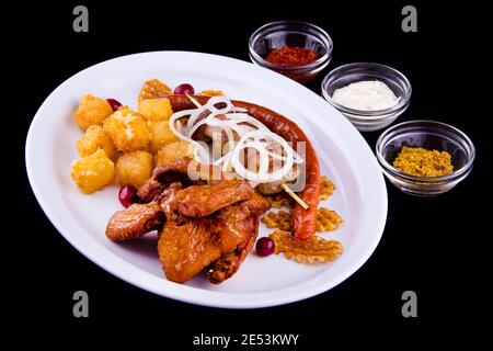 Large beer set of fried snacks - chicken wings, pork skewer, homemade sausages, potato chips, deep-fried cheese, onion, three sauces: white, red, must Stock Photo