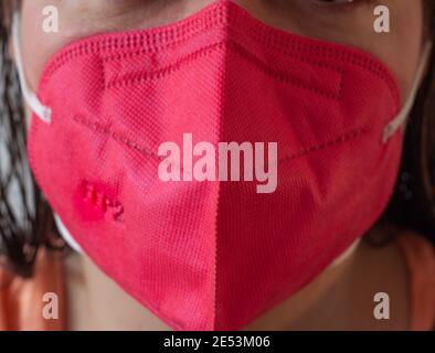 A red pink FFP2 mask against COVID  worn by a woman Stock Photo