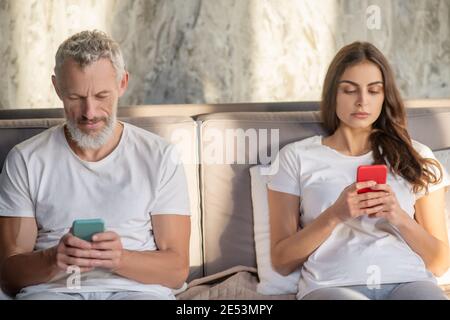 Concerned man and woman with their smartphones Stock Photo
