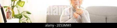 Elderly woman using asthma machine on light background Stock Photo