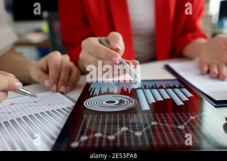 Business women studying charts and diagrams on digital tablet closeup Stock Photo