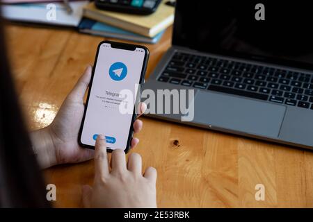 CHIANG MAI, THAILAND, JAN 23, 2021 : Woman hand holding iPhone with social networking service Telegram on the screen. iPhone 12 was created and Stock Photo