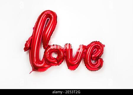 Red golden word LOVE made of inflatable balloons isolated on white background. Red foil balloon letters, concept of romance, Valentine's Day, Mothers Stock Photo
