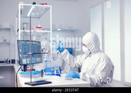 Researcher testing liquid sample uses micropipette in medical lab. Chemist in modern laboratory doing research using dispenser during global epidemic with covid-19. Stock Photo