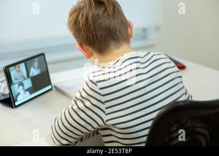 Teenager school boy having virtual lesson at home using tablet during homeschooling at pandemic quarantine Stock Photo