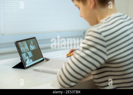 Teenager school boy having virtual lesson at home using tablet during homeschooling at pandemic quarantine Stock Photo