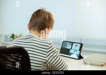 Teenager school boy having virtual lesson at home using tablet during homeschooling at pandemic quarantine Stock Photo
