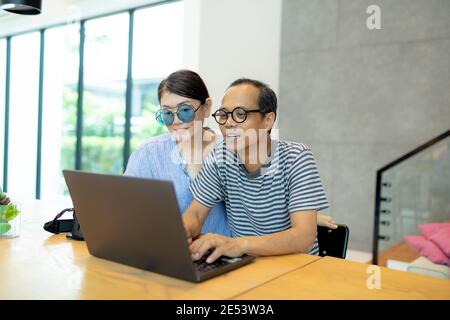 asian man and woman working on computer laptop at home living room Stock Photo