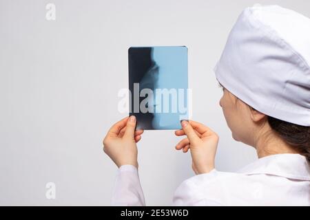 A doctor in white uniform examines an X-ray of a patient with a broken nose bone. Nose injury, crack or fracture - radiology and traumatology Stock Photo