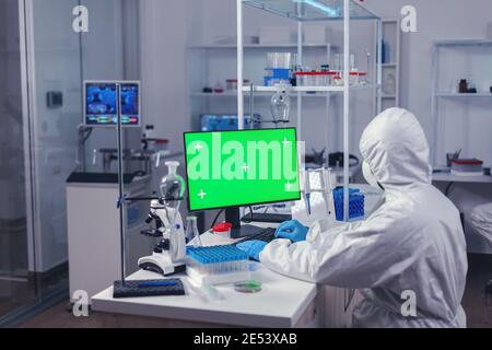 Medical engineer conducting research on computer with green screen during covornavirus. Team of microbiologists doing vaccine research writing on device with chroma key, isolated, mockup display. Stock Photo