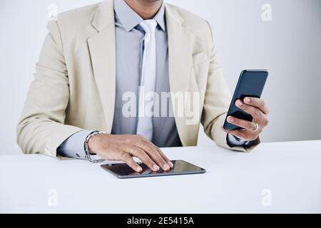 Hands of businessman checking text messages on smartphone and using mobile application on digital tablet Stock Photo