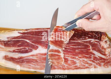 Freshly cut slice of acorn-fed Iberian ham, typical Spanish gourmet delicacy Stock Photo