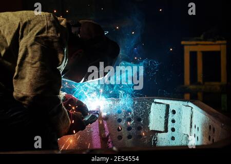 Worker in protective mask using angle grinder in workshop Stock Photo