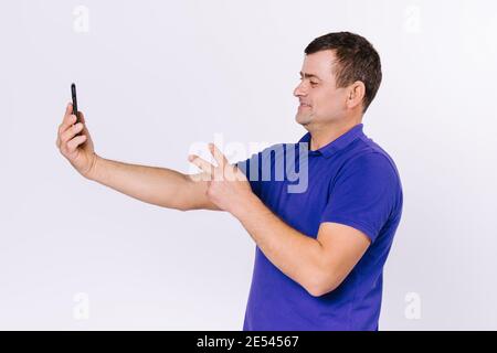 Smiling deaf senior man talking sign language on smartphone camera. White background. Stock Photo