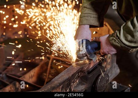 Close-up of worker using grinder for grinding metal in the plant Stock Photo