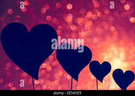 Valentines day concept and background. Silhouette heart shapes isolated on red and pink bokeh background. Stock Photo