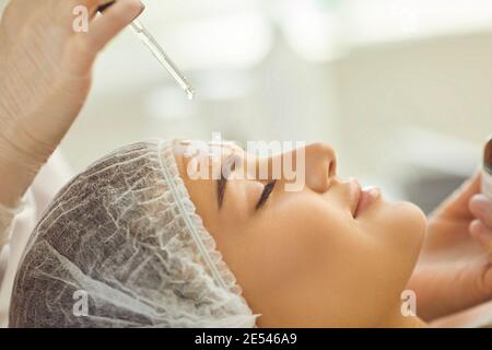 Smiling womans face getting skincare procedure of applying nourishing oil on skin Stock Photo