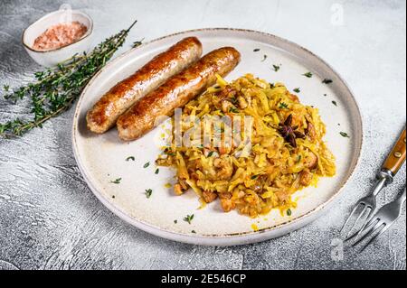 Stewed cabbage with mushrooms and meat sausages on a plate. White background. Top view Stock Photo