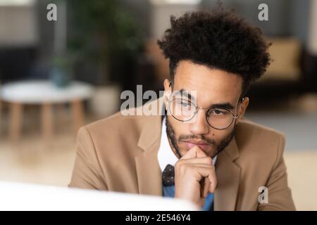 Close-up of pensive businessman in eyeglasses looking at computer monitor at office Stock Photo