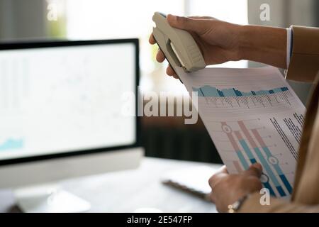 Close-up of man preparing his financial report and stapling documents with stapler Stock Photo