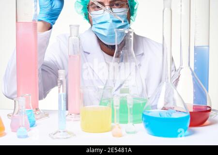Laboratory scientist technician wearing gloves, mask and lab coat working on research and conducting experiments in laboratory with test tubes and sub Stock Photo