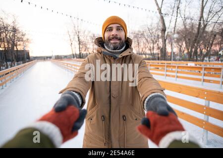 Portrait of young bearded man smiling at camera and skating with his girlfriend they holding hands Stock Photo