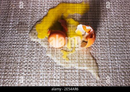 Broken egg on the floor on the tile - the egg shell and yolk spilled as a stain on the floor Stock Photo