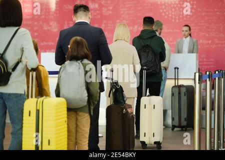 Rear view of people standing with luggages in a queue and waiting for departure of the plane Stock Photo