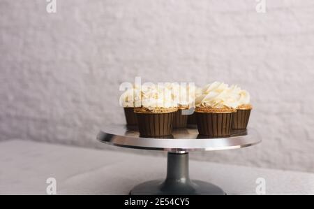 the chef girl sprinkles icing on fresh cupcakes covered in vanilla cream.Sweet homemade cupcakes with cream on a tray. Food for breakfast. Freshly Stock Photo