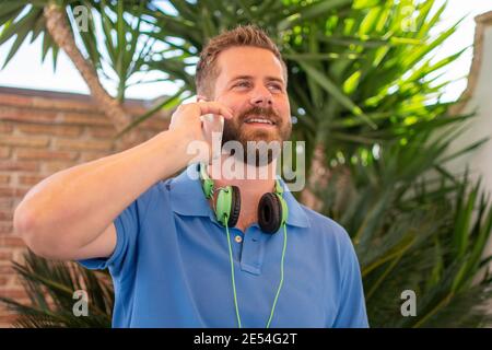 Young man wearing headphones talking on his phone outdoors Stock Photo
