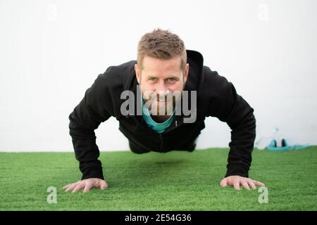 Determined strong young man doing push-ups and looking at camera Stock Photo