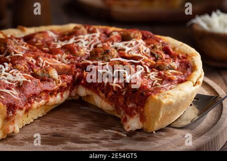 Closeup of a deep dish sausage pizza on a wooden platter Stock Photo
