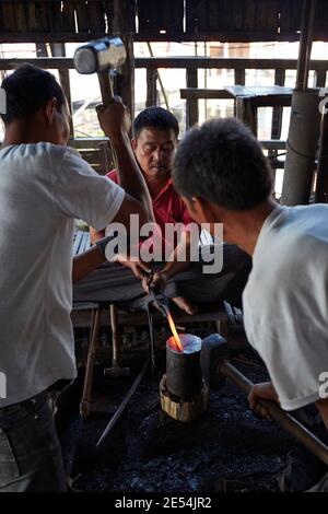 Blacksmiths at work forging iron/steel in a local workshop on Inle Lake, Myanmar. Stock Photo
